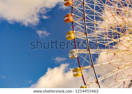 Giant amusement wheel against blue sky and white clouds