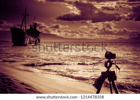 Professional camera on tripod taking picture film video from greek coastline with rusty shipwreck Dimitrios near Gytheio, Gythio Laconia Peloponnese Greece.
