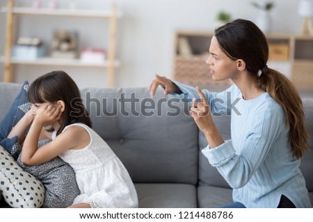 Side view single mother screams shouts at little daughter scolding her. Kid not listen ignoring mom close cover her ears with fingers. Complicated relationships with child and family conflict concept Royalty-Free Stock Photo #1214488786