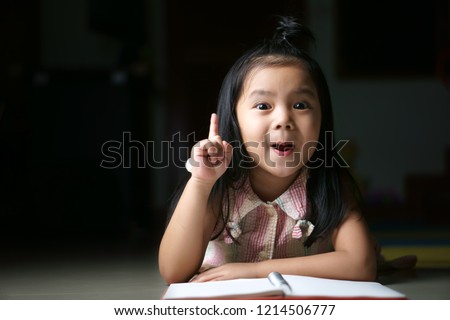 Asian child or kid girl student sleep reading and thinking for new idea with wow open mouth on homework and diary or book at children kindergarten classroom or nursery preschool in home on black space Royalty-Free Stock Photo #1214506777