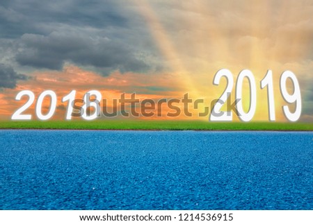 Asphalt road surface blue, Green lawn and the twilight sky between 2018 before enters new year 2019, and last sun of day, With concept of starting New goals and changes in life.