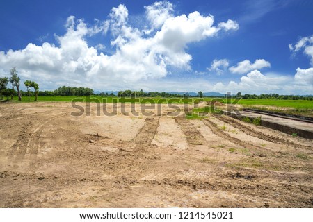 Empty reclamation area, vacant compact soil of construction site with car tire printed and beautiful landscape view and blue sky. Land plot for sales and real estate development sale project concept Royalty-Free Stock Photo #1214545021