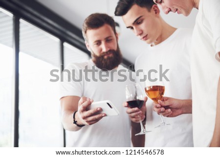 Cheerful old friends communicate with each other and phone watch, with glasses of whiskey or wine in pub. Concept of entertainment and lifestyle. Wifi connected people in bar table meeting.