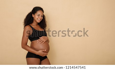 Side view of happy pregnant woman holding her belly Royalty-Free Stock Photo #1214547541