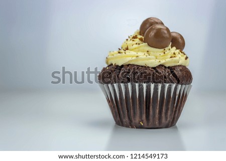 Food Theme, view of isolated and delicious white and black cupcake with shavings of chocolate and balls on top , white background