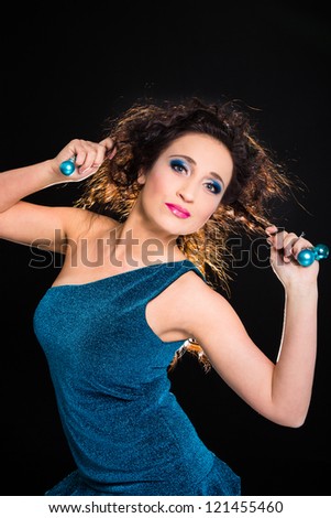 beautiful girl wearing turquoise dress playing with Christmas decoration on black background
