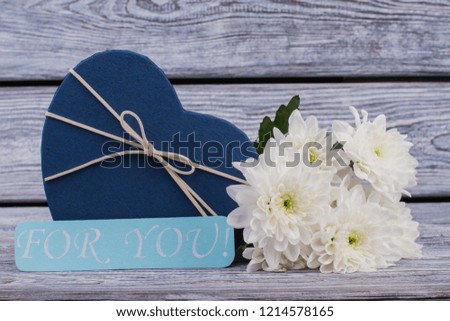 Romantic background with flowers and gift box. Valentines Day background with present box in a shape of heart and beautiful chrysanthemums on wooden table.