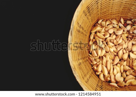 Group of garlic cloves in bamboo winker basket on black background.It is  popular for healthy ingredient in Thai food.Garlic smell is very strong and make food tasty.Good for health.Top view.