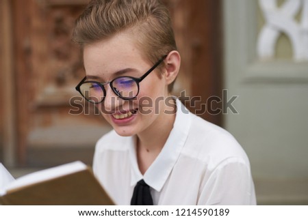 smiling woman with glasses looks into a book                       