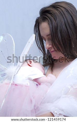 Mother holding her baby daughter wearing butterfly/angel wings.