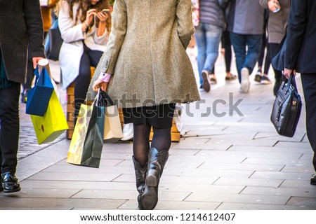 A shopping high street scene with woman carrying shopping bag Royalty-Free Stock Photo #1214612407