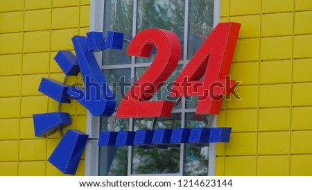 Yellow convenience store with a blue clock and big red numbers 24 hour service.