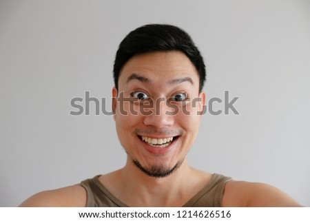 Happy funny smile face of Asian man taking selfie photo of himeself.