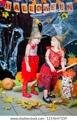 Children, little witch-shaped girls on a broomstick, pose against the backdrop of cobweb landscapes, pumpkins and autumn leaves at the Halloween feast.