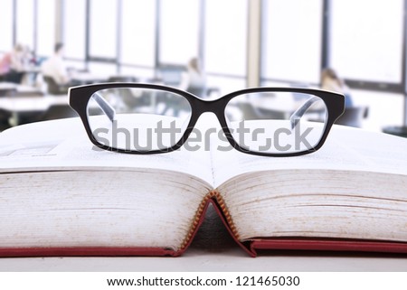 Picture of an open book with a glasses on top of it