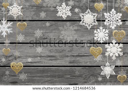 Christmas and New Year decorations: snowflakes and golden hearts on gray wooden background.