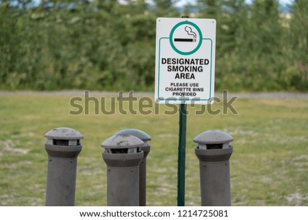 Sign for a designated smoking area with cigarette bins ashtrays