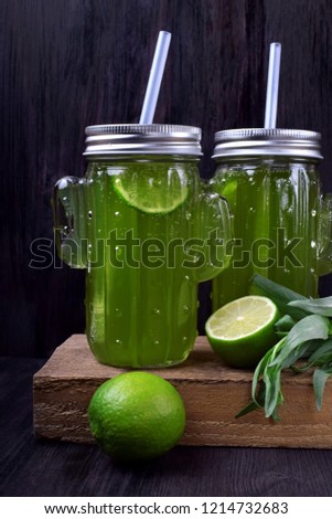 Two glass jars of green lemonade with tarragon and lime
