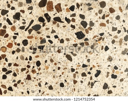 Closeup of polished stones laid in white cement.  Earthy and subtle color variations.