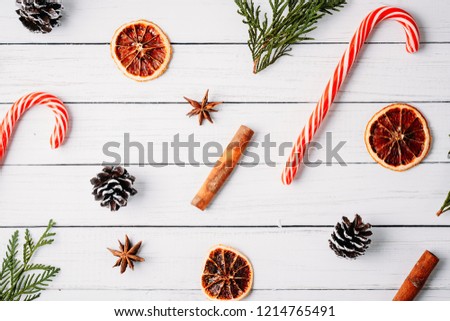Composition of dried oranges, pine cones, cinnamon and candy sweet on white wooden background