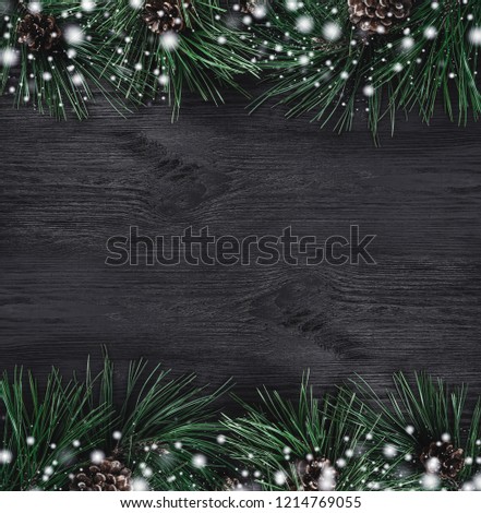 Christmas card. Black wood background with pine branches and pine cones from the top, top view. Xmas square card. Snow effect. Royalty-Free Stock Photo #1214769055