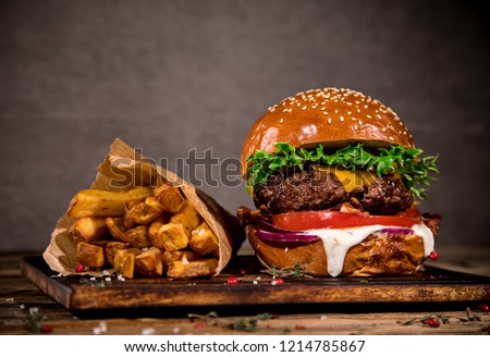 Close-up of home made tasty burger with french fries on wooden table. Royalty-Free Stock Photo #1214785867