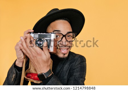 Close-up portrait of male photographer with brown eyes and dark skin. Smiling african man working in studio with camera.