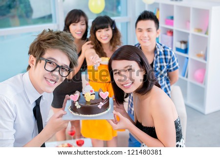 Happy teenagers showing their birthday cake