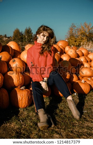 Young woman on a pumpkin farm. Beautiful girl near pumpkins. A girl with a pumpkin
