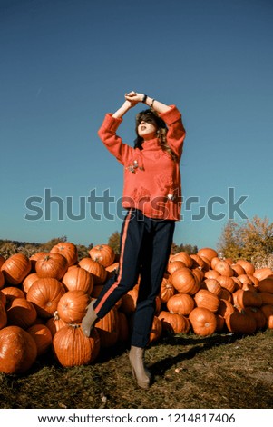 Young woman on a pumpkin farm. Beautiful girl near pumpkins. A girl with a pumpkin