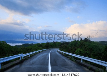 Open road curves through forest under beautiful early morning sky