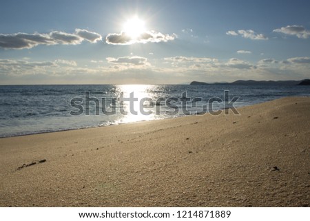the Golden beach along the calm blue sea under a clear sky with white clouds and shining sun