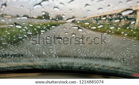 blurred view of road traffic on a rainy day through the car window. raindrops on the glass window of the car.