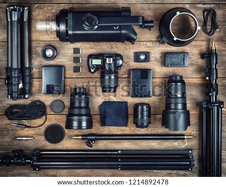 Set of the camera and photography equipment ( tripod, filter, flash, camera lens, memory card, hard desk, reflector) on wood desk. Professional photographer accessories background.