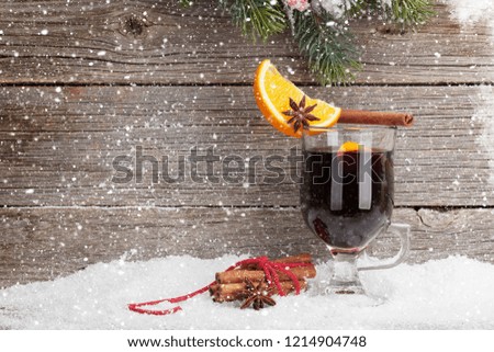 Christmas card with mulled wine hot drink and xmas fir tree branch covered by snow. With space for your greetings