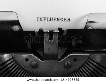 INFLUENCER, title heading typewritten in all caps, on white paper on vintage manual typewriter machine, business, career, occupation concept