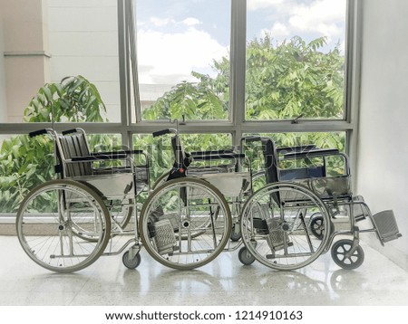 Empty wheelchair parked in front of hospital window.
