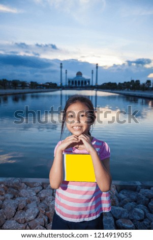 Smiling young girl with holding a empty box on mosque background
