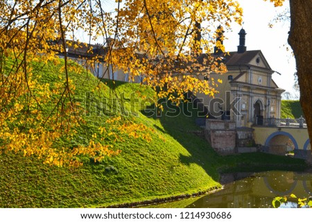 Old, ancient medieval castle with spiers and towers, walls of stone and brick surrounded by a protective moat with water in the center of Europe. Baroque style architecture.
