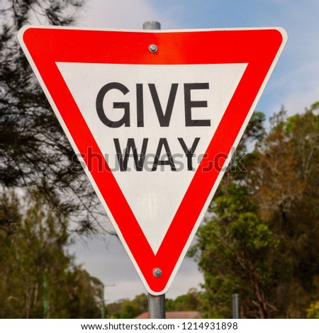 Give Way! sign against a blue sky and Australian bush. Australian signs found along the road on road trips - inspiration for adventure, travel memories and brochures of signs in Australia for tourists