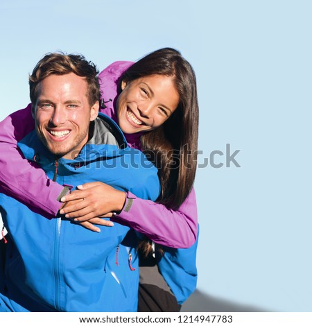 Happy hikers couple living an active lifestyle hugging laughing outdoors on trek hike nature. Healthy young people adventure fun wearing jackets. Interracial relationship, Asian woman, Caucasian man Royalty-Free Stock Photo #1214947783