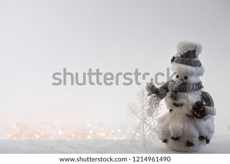 Toy snowman on a background of blurry Christmas lights. Copy space.