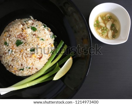 Top view picture of pork fried rice on black plate above black texture. 