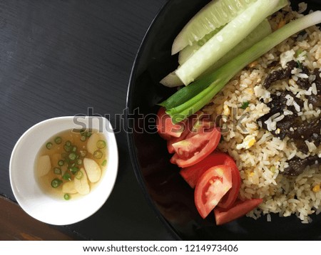Top view picture of beef fried rice on black plate above black texture. 