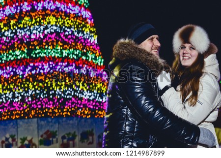 a young smiling happy couple hugging on Christmas Street