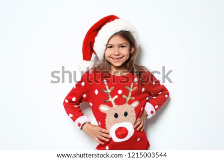 Cute little girl in Christmas sweater and hat on white background