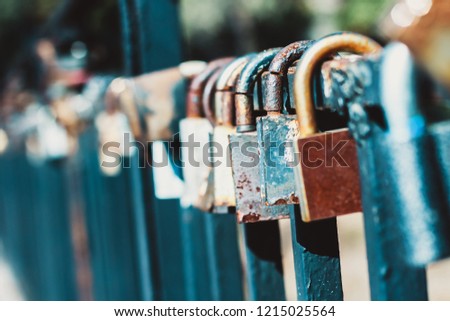 Old corroded love padlocks hanging on the railings of the bridge. Shallow depth of field.