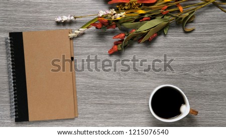 Blank note carton brown cover with flowers and black coffee on flat flay wood background with blank copy space ideal for company product marketing message