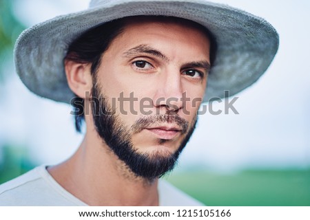 Style and vacation concept. Outdoor portrait of handsome young man with  beard and hat.