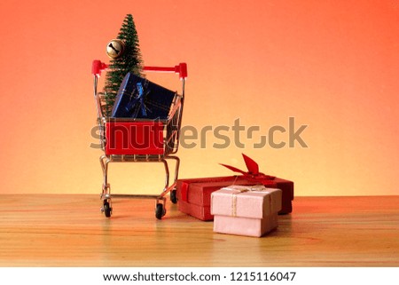 NEW YEAR CONCEPTUAL with shopping trolley,gift boxes and Christmas tree on a wooden table.